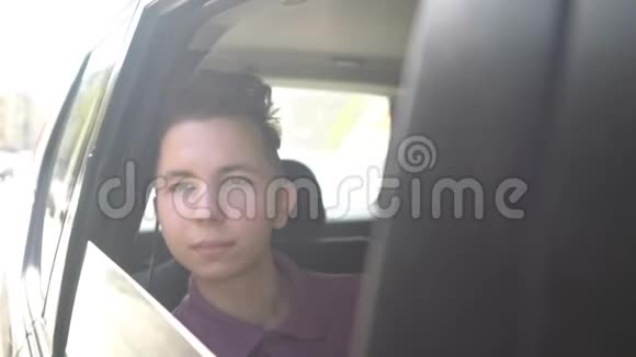 阳光明媚的一天年轻英俊的少年乘出租车和司机一起旅行视频的预览图