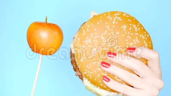 健康和不健康食品的概念雅洛科在明亮的蓝色背景上对抗汉堡包红色指甲的雌手视频的预览图