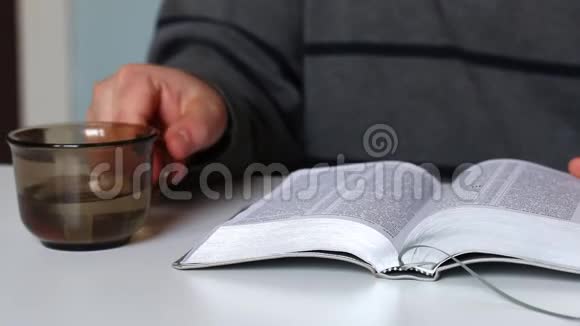 一个人读圣经翻过书页从杯子里喝水视频的预览图