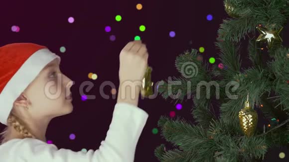 年轻的白种人女孩带着戴着红色圣诞帽的父亲用金球球装饰着绿色的圣诞树视频的预览图