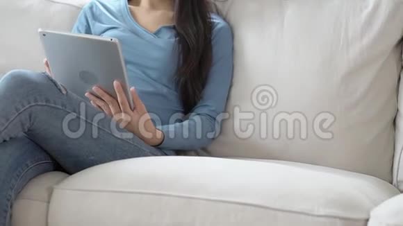 美丽的肖像年轻的亚洲女性微笑使用数字平板电脑坐在客厅的沙发上视频的预览图