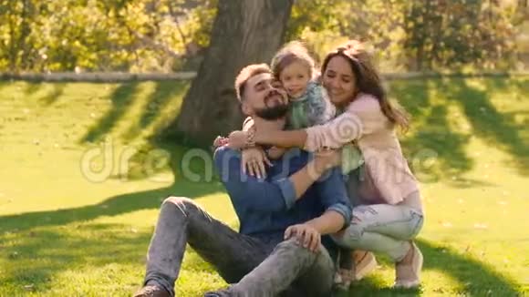 笑着一家人互相拥抱一边坐在绿茵场上视频的预览图