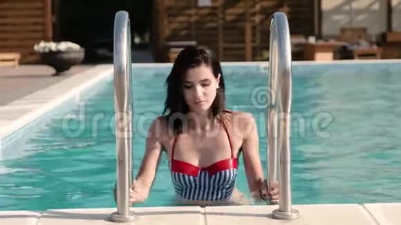 一位身穿泳装的年轻美女优雅地从游泳池里走出来视频的预览图