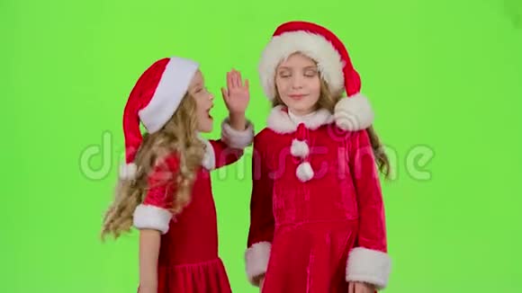 两个穿着新年服装的女婴互相讲述秘密绿色屏幕视频的预览图