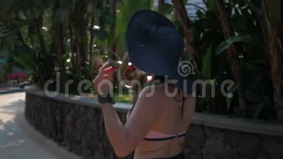 一个戴着蓝色帽子的漂亮女孩去热带城市夏日的阳光慢动作视频的预览图