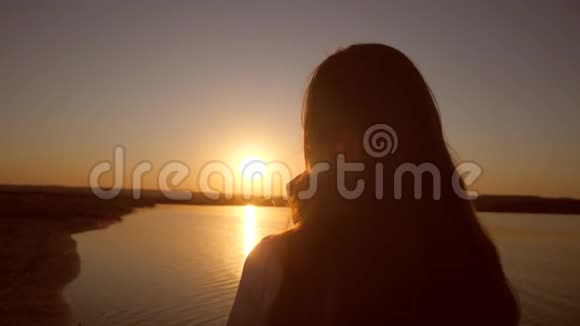 日落时分海滩上的女孩在打电话视频的预览图