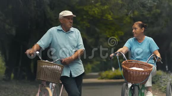 两个骑自行车的老人在公园里交谈视频的预览图