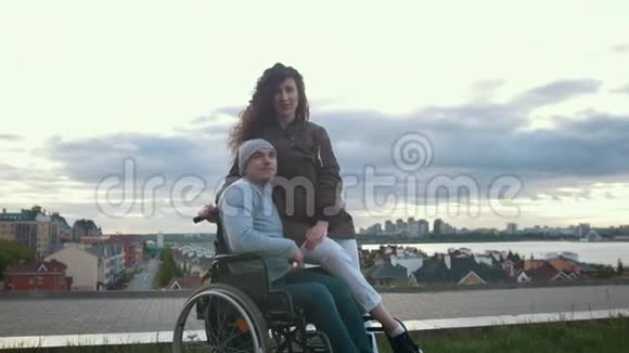 一位坐轮椅的快乐残疾人与户外年轻女子拥抱的肖像视频的预览图