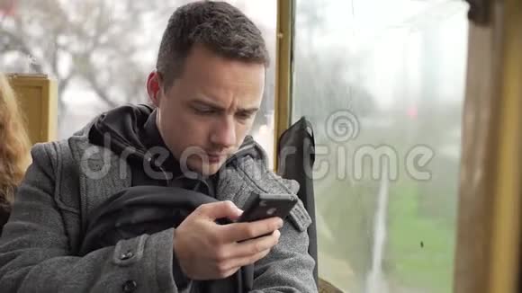 一个年轻人坐在电车上用他的电话视频的预览图
