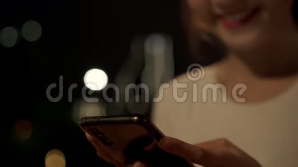 亚洲旅游博客女性使用触摸屏技术在智能手机而在市中心的街道上行走在夜间视频的预览图