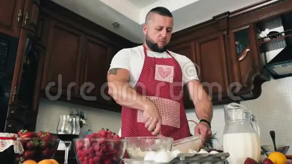 年轻的肌肉男把鸡蛋加到生面团里做煎饼视频的预览图