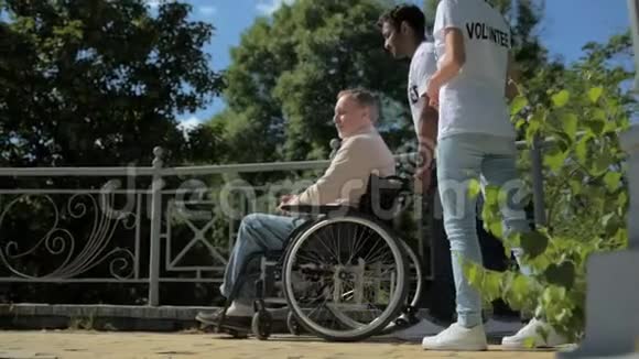 一位乐于助人的志愿者带着轮椅行走视频的预览图