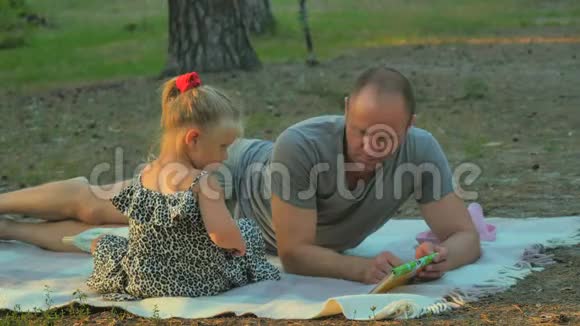 父亲和女儿在森林里野餐时等着一位带着篮子和食物的母亲视频的预览图