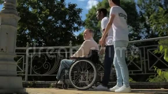 积极的青年志愿者帮助一个坐轮椅的人视频的预览图