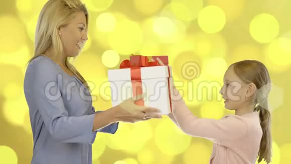 一个女孩和一个年轻的女人正在为度假送礼物盒黄金背景闪闪发光视频的预览图