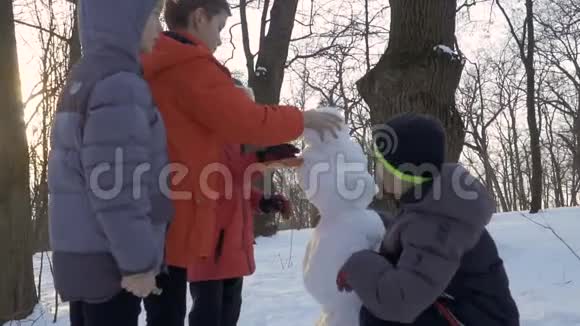 男孩子们在冬季公园堆雪人慢镜头视频的预览图