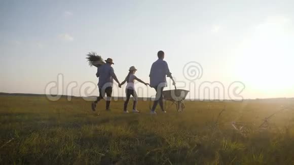 年轻的家庭在他们的农场户外玩得很开心日落时分园丁妇女用蔬菜推着手推车家庭视频的预览图