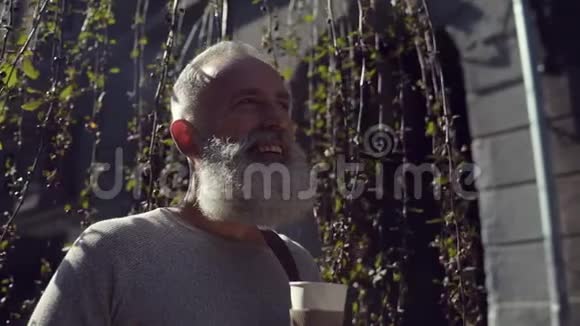 英俊的大胡子男人在户外喝着美味的咖啡视频的预览图