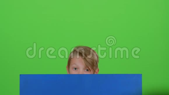 十几岁的孩子从黑板后面站起来看着它在绿色的屏幕上表示不喜欢视频的预览图