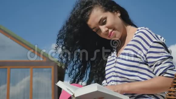 迷人的黑发女人在天空中看书视频的预览图