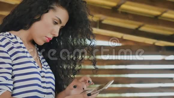 漂亮的卷发女孩通过手机短信交流视频的预览图