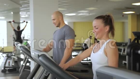 在跑步机上男人和女人开始在健身房的跑步机上跑步视频的预览图