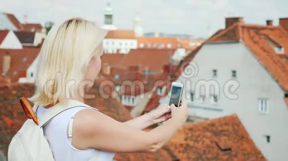 一位女游客为美丽的格拉茨市的老城区拍照在图片中可以看到红瓦屋顶视频的预览图