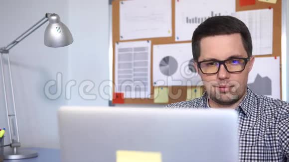 在办公室里用笔记本电脑工作一个男人的脸部特写镜头视频的预览图