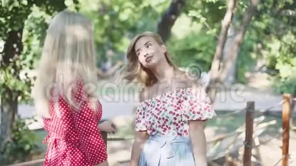 两个年轻迷人的女人在公园里聊天和散步日落公园里的姐妹们视频的预览图