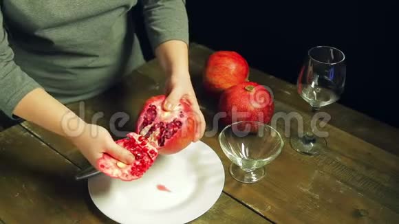女人在木桌上的白色盘子上清洗石榴果实视频的预览图