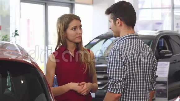年轻漂亮的女人在经销店和她的男人聊天视频的预览图