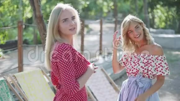 两个年轻迷人的女人在公园里聊天和散步日落公园里的姐妹们视频的预览图