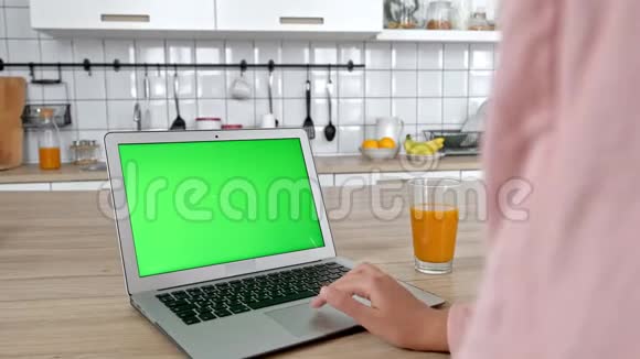 漂亮的黑发女人看着笔记本电脑屏幕吃着苹果坐在家里的内部年轻的女人穿着休闲装视频的预览图