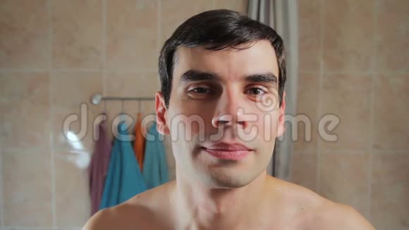 站在浴室里的一个英俊的干净胡子男人的肖像男孩微笑着站在镜子前视频的预览图