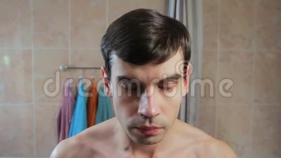 男人脸上有剃须泡沫他开始在镜子前刮胡子看着自己视频的预览图