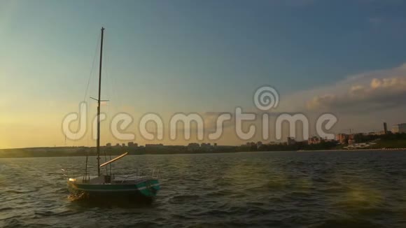 在城市海湾码头上的一艘小帆船日落美丽的傍晚景观慢动作视频的预览图