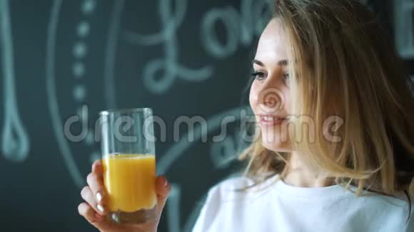 年轻的美女喝果汁女孩早上早餐喝新鲜的橘子视频的预览图