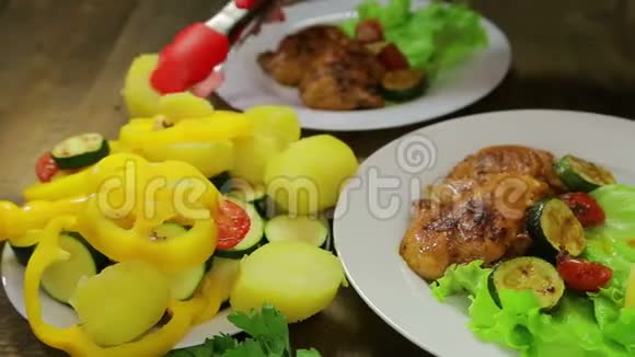 女人的手把蔬菜片放在一个盘子里里面有绿色沙拉和鸡肉视频的预览图