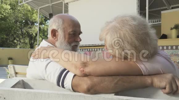 在爱情中老两口在夏天的电影院里在长凳上聊天视频的预览图