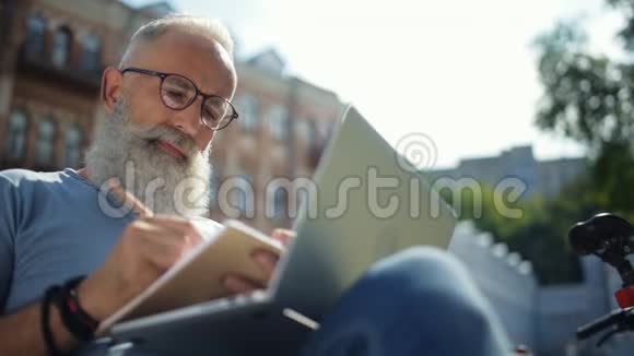 放松的成熟男人在户外工作时注意到视频的预览图