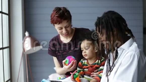 可爱的混血幼儿和父母一起玩视频的预览图