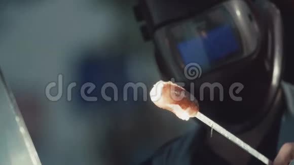 男性佩戴焊接头盔是燃烧厚厚的香肠放在工作场所的扦子上视频的预览图