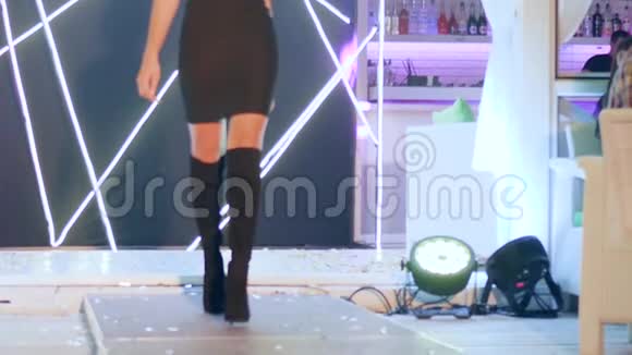 穿着优雅礼服穿着时尚绒面靴子的女孩优雅地走在时装秀的T台上视频的预览图