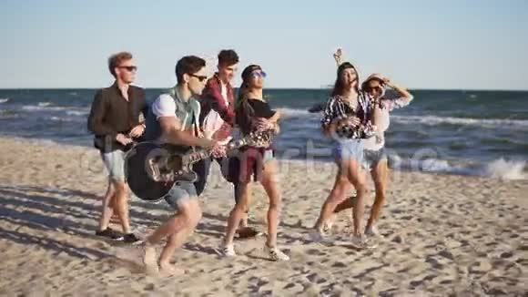一群年轻的嬉皮士朋友一起在沙滩上玩吉他和唱歌跳舞视频的预览图