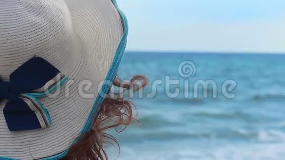 在海边的阳光沙滩上放松享受海景的女帽特写视频的预览图