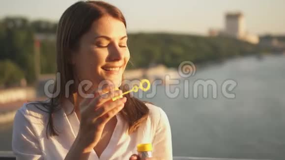 快乐的年轻女人在户外放松漂亮的女孩吹着肥皂泡夏日的阳光灿烂视频的预览图