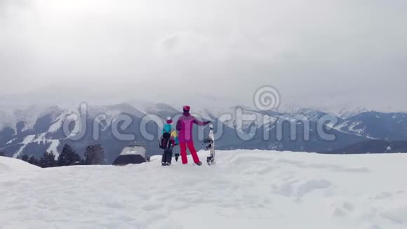 幸福的家庭在山上享受寒假家庭滑雪度假人们观察山景视频的预览图