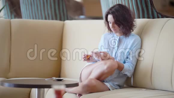 年轻模特用智能手机躺在沙发上喝酒视频的预览图