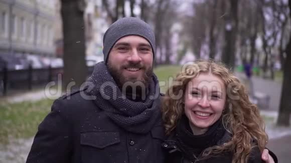 大胡子和卷发女孩看着镜头在冬天的公园里微笑视频的预览图