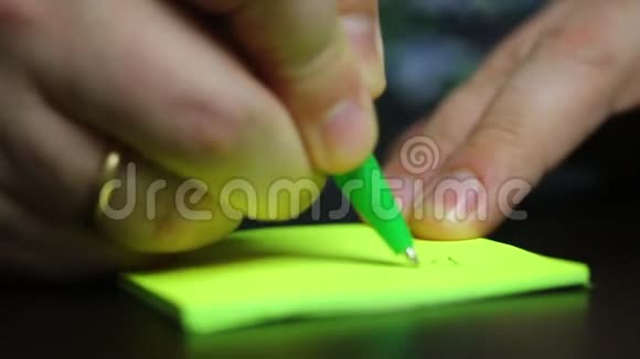 一个人在贴纸上写字然后把它粘在桌子上特写镜头视频的预览图